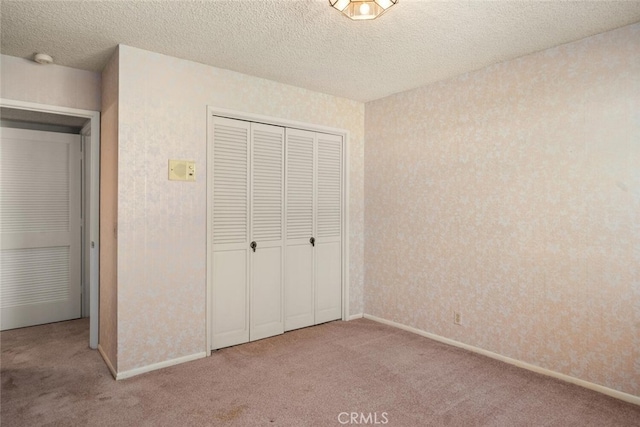 unfurnished bedroom with baseboards, carpet flooring, a closet, and a textured ceiling