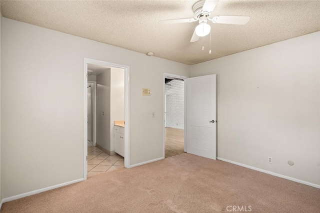 unfurnished bedroom with ensuite bathroom, light carpet, baseboards, and a textured ceiling