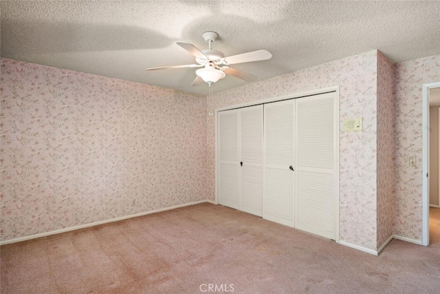 unfurnished bedroom with a textured ceiling, a closet, wallpapered walls, and carpet floors