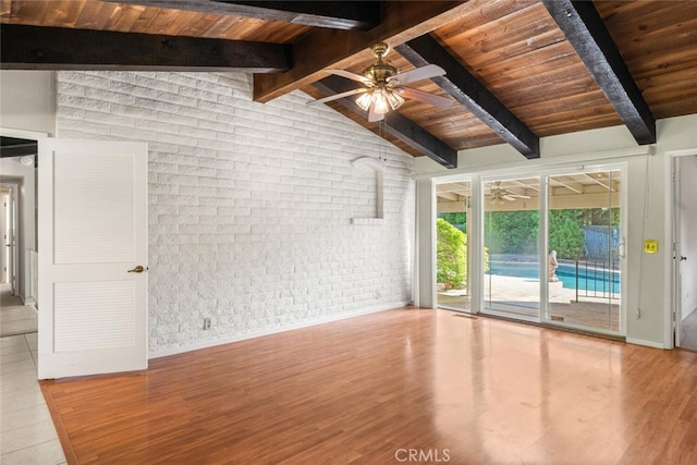 unfurnished living room featuring wood ceiling, lofted ceiling with beams, ceiling fan, and brick wall