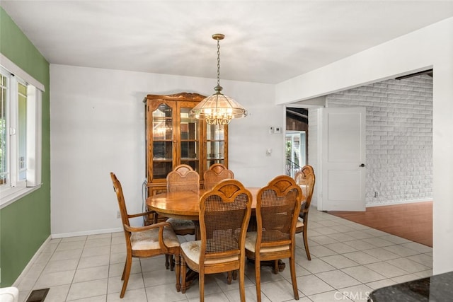 dining room featuring light tile patterned floors, a notable chandelier, brick wall, and visible vents