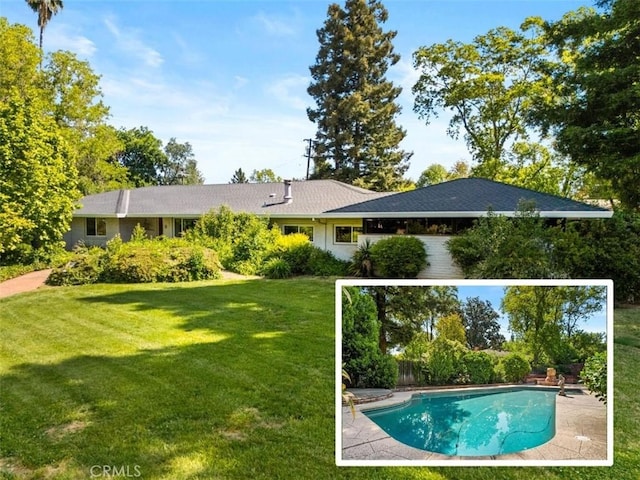 rear view of house with a yard and an outdoor pool