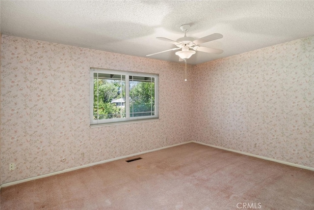 carpeted spare room with a textured ceiling, a ceiling fan, and visible vents