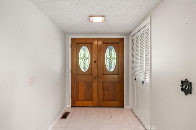 entryway featuring baseboards, light tile patterned floors, visible vents, and a textured ceiling
