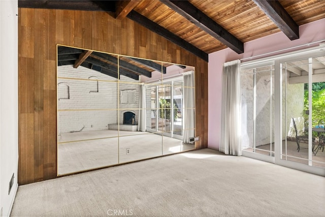 unfurnished living room with carpet, brick wall, vaulted ceiling with beams, wood walls, and wooden ceiling