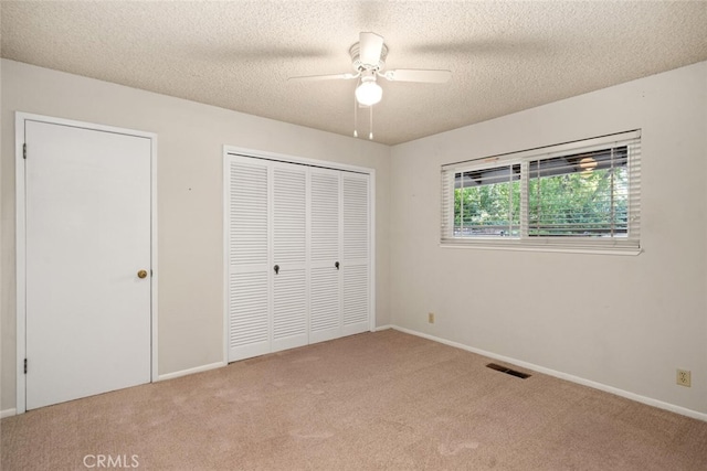 unfurnished bedroom featuring carpet, a closet, a textured ceiling, visible vents, and baseboards