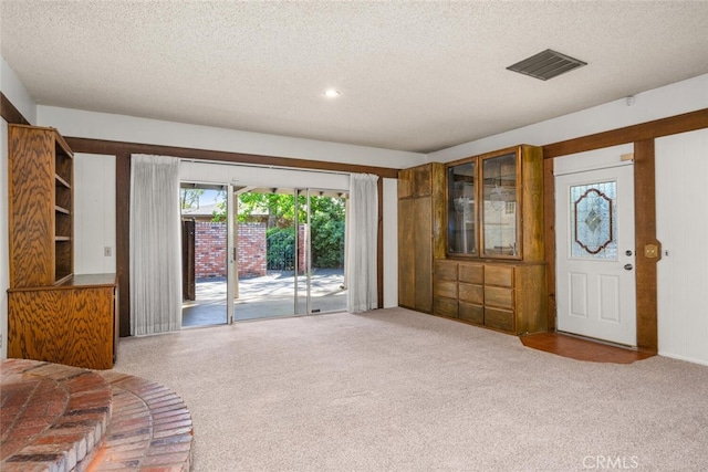 unfurnished living room with carpet floors, visible vents, and a textured ceiling