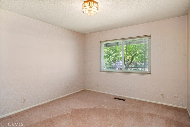 spare room featuring a textured ceiling, visible vents, and carpet floors