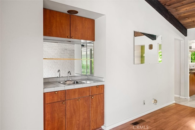 bar with a sink, lofted ceiling, wood ceiling, and a healthy amount of sunlight