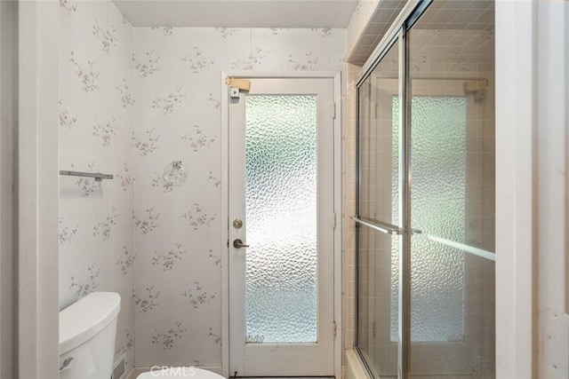 full bathroom with wallpapered walls, toilet, a wealth of natural light, and tiled shower