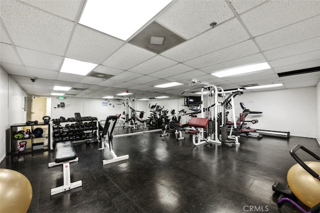 workout area featuring a paneled ceiling and baseboards