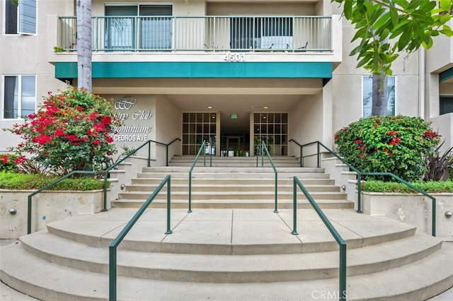 property entrance with a balcony and stucco siding