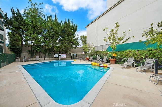 community pool with fence and a patio area