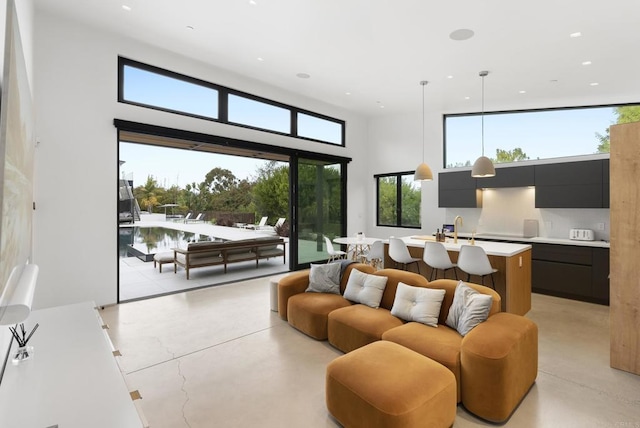 living room with concrete floors, recessed lighting, and a high ceiling