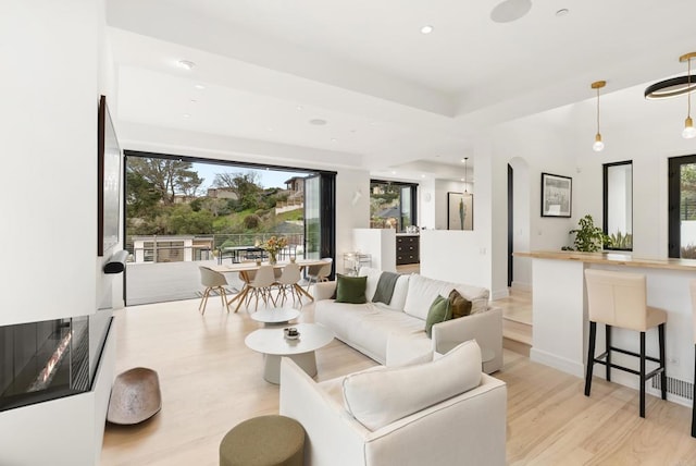 living area with light wood-type flooring, arched walkways, and recessed lighting