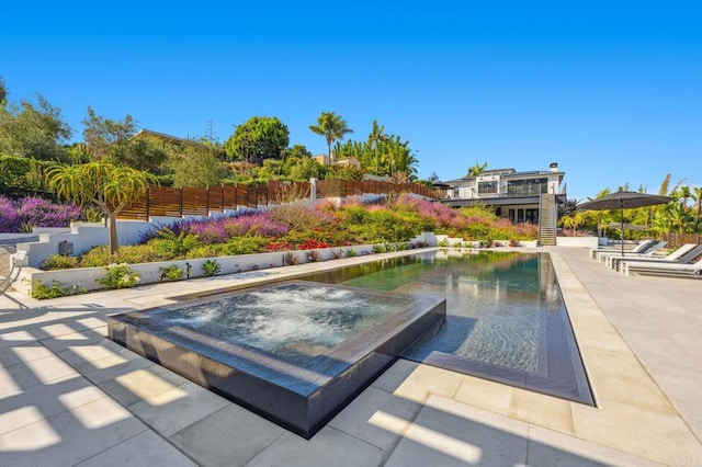 outdoor pool featuring a patio area, an in ground hot tub, and fence