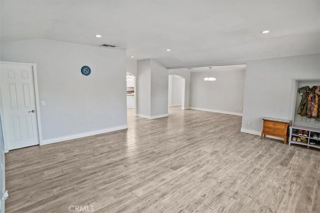 unfurnished living room with visible vents, baseboards, light wood-type flooring, recessed lighting, and arched walkways