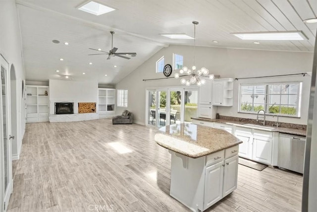 kitchen featuring a center island, white cabinetry, a sink, dishwasher, and a skylight