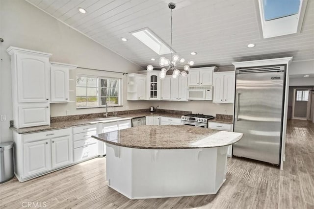 kitchen with a skylight, appliances with stainless steel finishes, open shelves, a sink, and white cabinetry