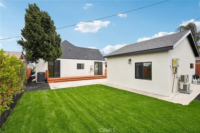 rear view of house with a lawn, fence, stucco siding, and central air condition unit