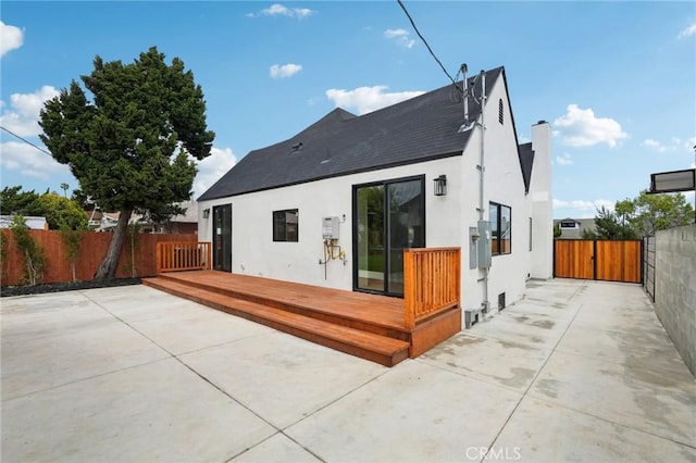 rear view of property featuring a patio, a wooden deck, stucco siding, and fence