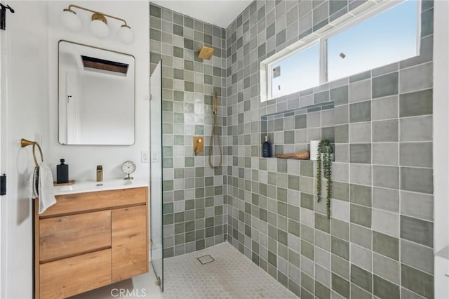 full bath with a tile shower and vanity