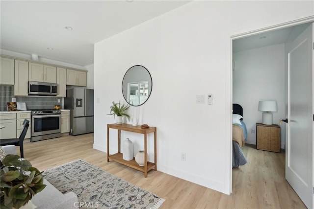 kitchen with backsplash, light wood-style floors, and appliances with stainless steel finishes