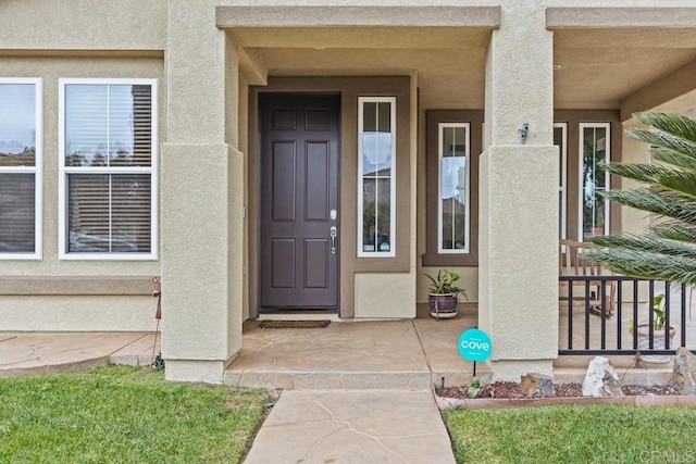 view of exterior entry featuring stucco siding and covered porch