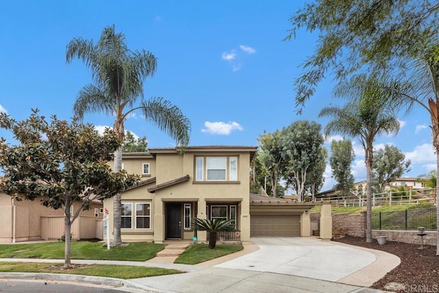 traditional-style home featuring stucco siding, fence, a front yard, concrete driveway, and an attached garage