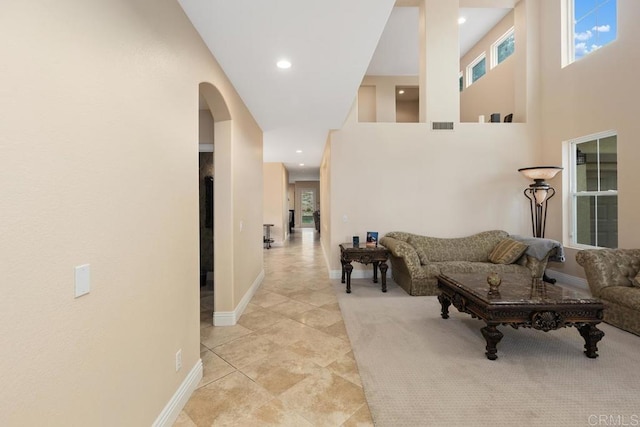 living room featuring light tile patterned flooring, arched walkways, visible vents, and baseboards