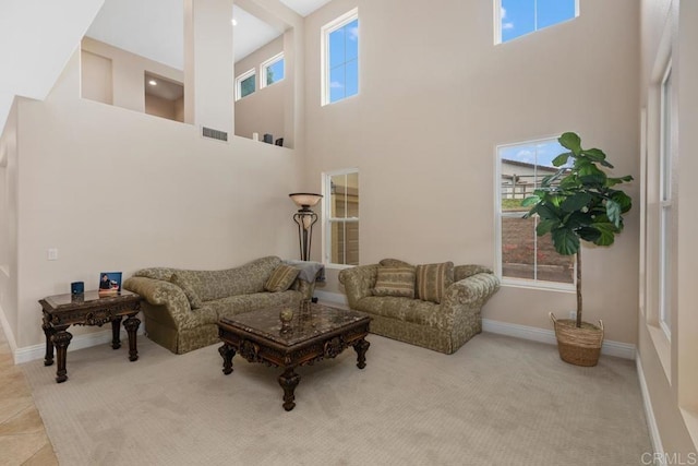 living room featuring visible vents, a healthy amount of sunlight, and a high ceiling
