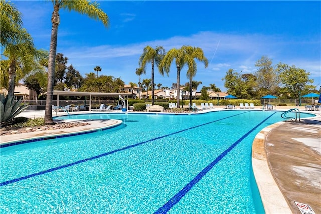 community pool with a patio area and fence