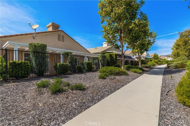 view of front of home featuring fence, a chimney, and stucco siding