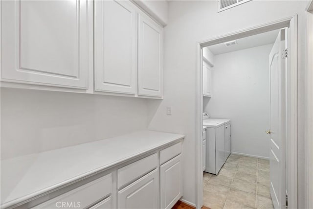 clothes washing area featuring cabinet space, separate washer and dryer, and visible vents