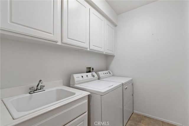 clothes washing area featuring baseboards, a sink, cabinet space, and washing machine and dryer