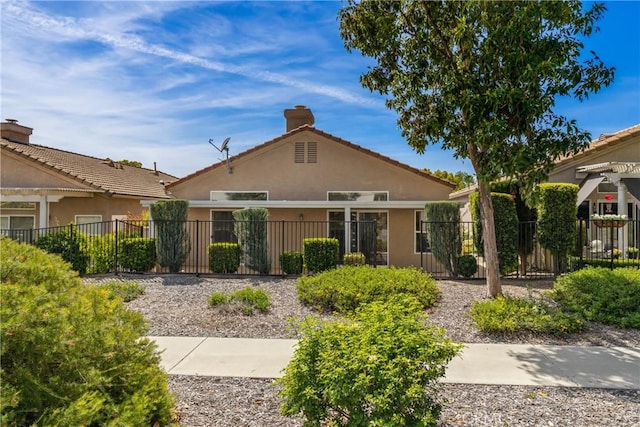 back of property featuring a fenced front yard, stucco siding, and a chimney