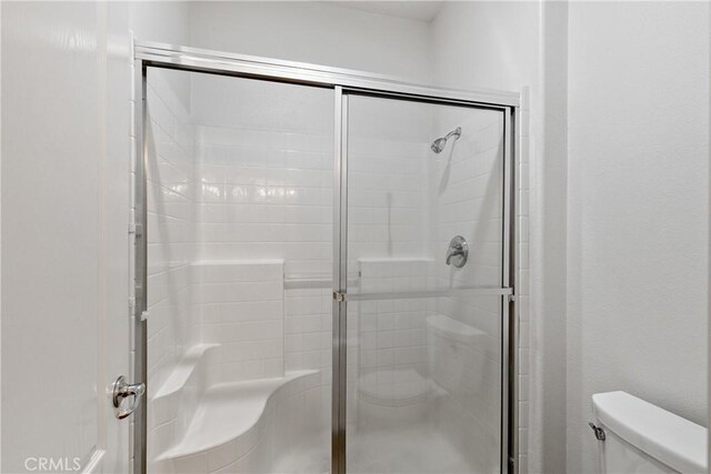 bathroom with toilet and a stall shower
