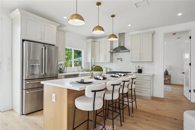 5449 S Victoria Ave, Los Angeles, CA 90043 - kitchen with wall chimney range hood, tasteful backsplash, appliances with stainless steel finishes, visible vents, and light wood-type flooring