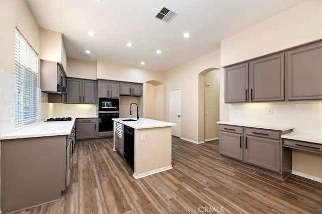 kitchen featuring a sink, black appliances, visible vents, backsplash, and arched walkways