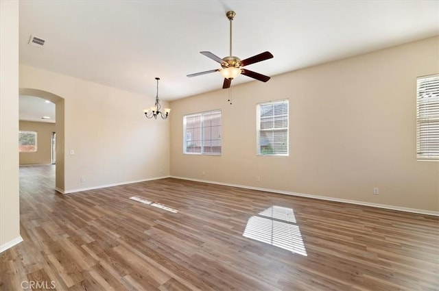 unfurnished room featuring visible vents, baseboards, arched walkways, wood finished floors, and ceiling fan with notable chandelier