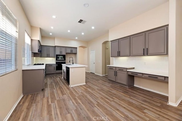kitchen featuring visible vents, arched walkways, wood finished floors, and a sink