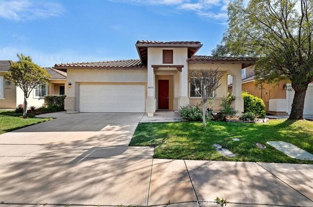 mediterranean / spanish house with stucco siding, an attached garage, and a tile roof