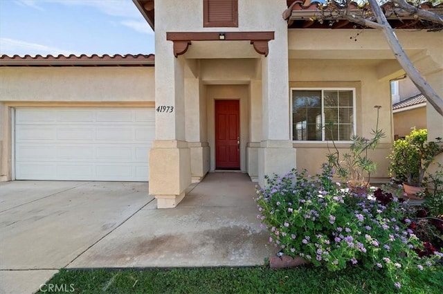 doorway to property with a garage, stucco siding, and driveway