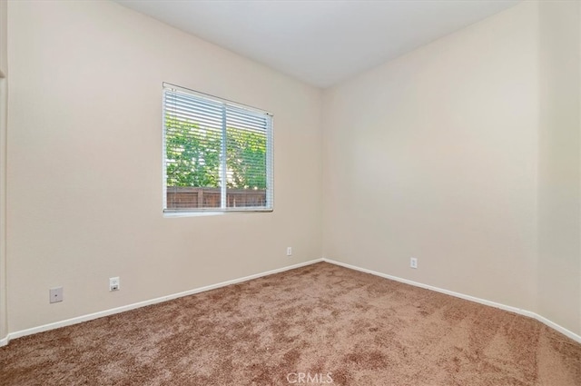 carpeted spare room featuring baseboards