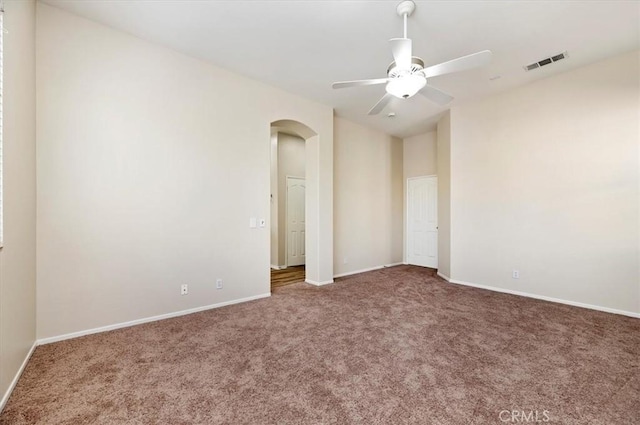 unfurnished bedroom featuring baseboards, visible vents, arched walkways, and carpet