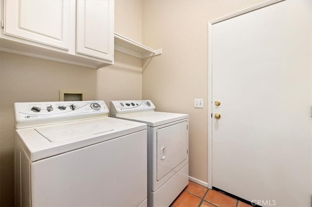 clothes washing area featuring baseboards, cabinet space, washing machine and clothes dryer, and light tile patterned flooring