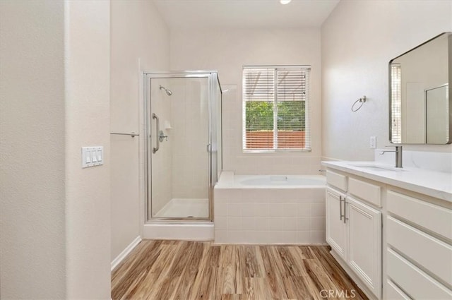 bathroom with wood finished floors, a shower stall, a bath, and vanity