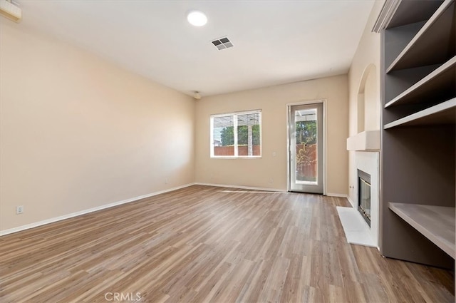 unfurnished living room with recessed lighting, light wood-type flooring, a fireplace, baseboards, and visible vents