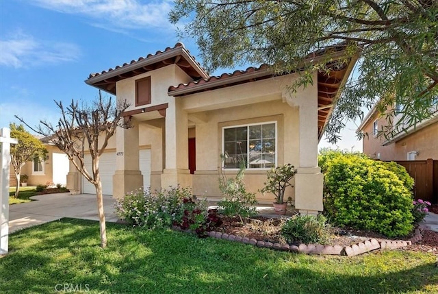 mediterranean / spanish home featuring fence, concrete driveway, a tiled roof, stucco siding, and a front lawn