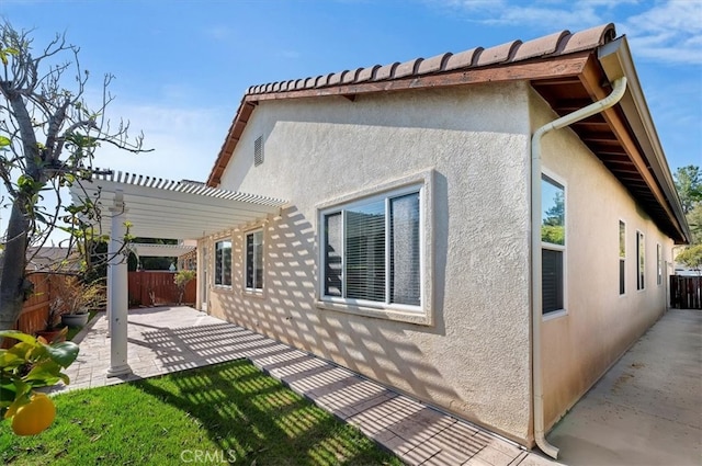 rear view of house featuring stucco siding, a pergola, a patio, and a fenced backyard